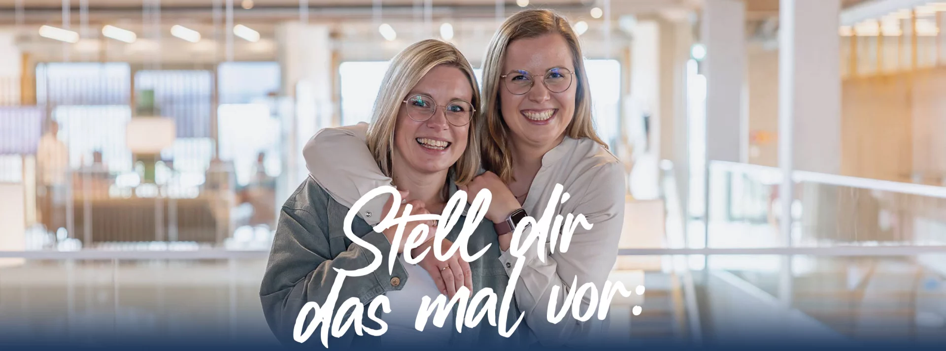 Zwei junge Frauen im Büro kumpelig umarmt