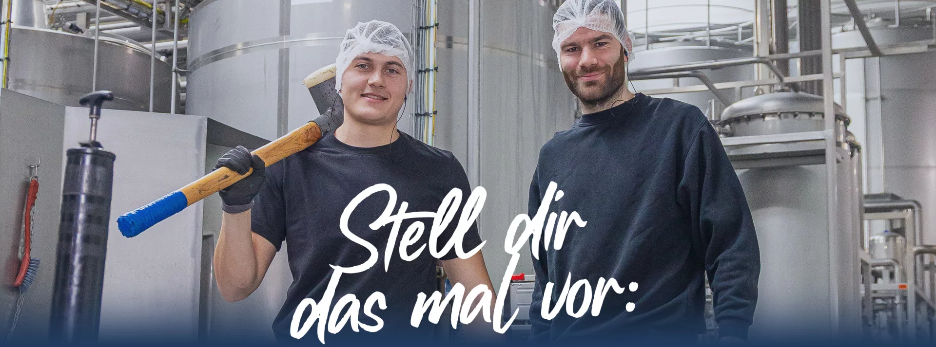 Mentor/Auszubildender mit einem großen Hammer in der Produktion